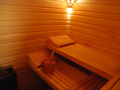 Blick auf Saunabänke mit glühendem Ofen und Aufgußeimer